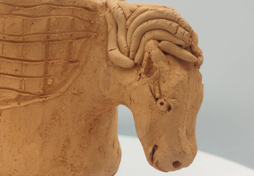 Close-up of the ceramic horse’s head with a modelled mane, eye and muzzle.