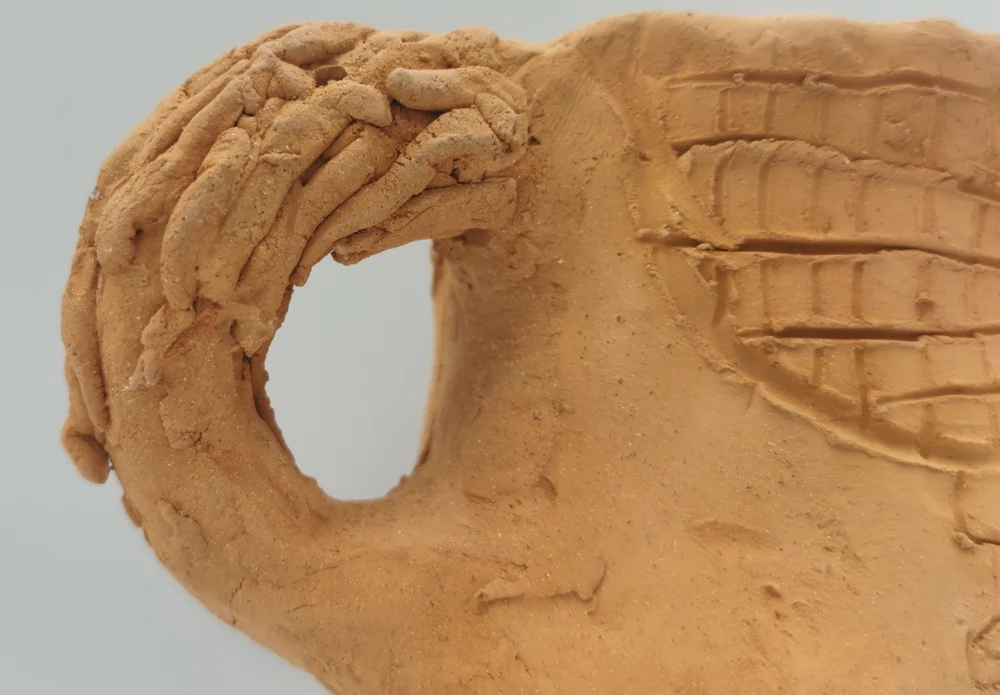 Close-up of the curved ceramic cup handle combined with the sculpted tail of the horse.