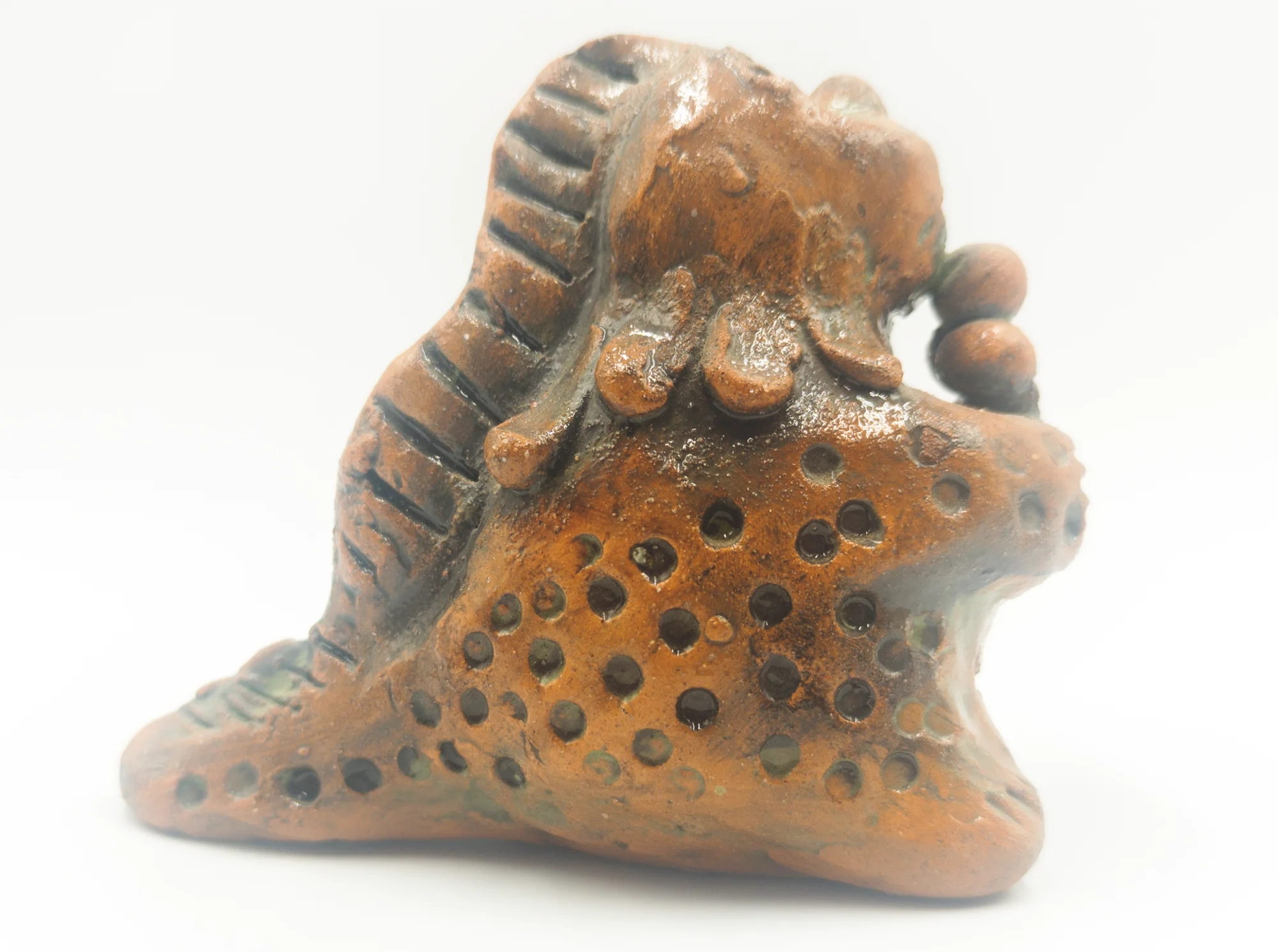 Glazed ceramic dinosaur seen from the opposite side, showing its head, front limbs, ice cream and long tail.