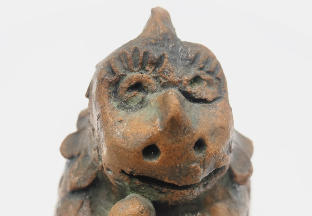 Close-up of the glazed ceramic dinosaur’s face, with raised eyes and a small horn.